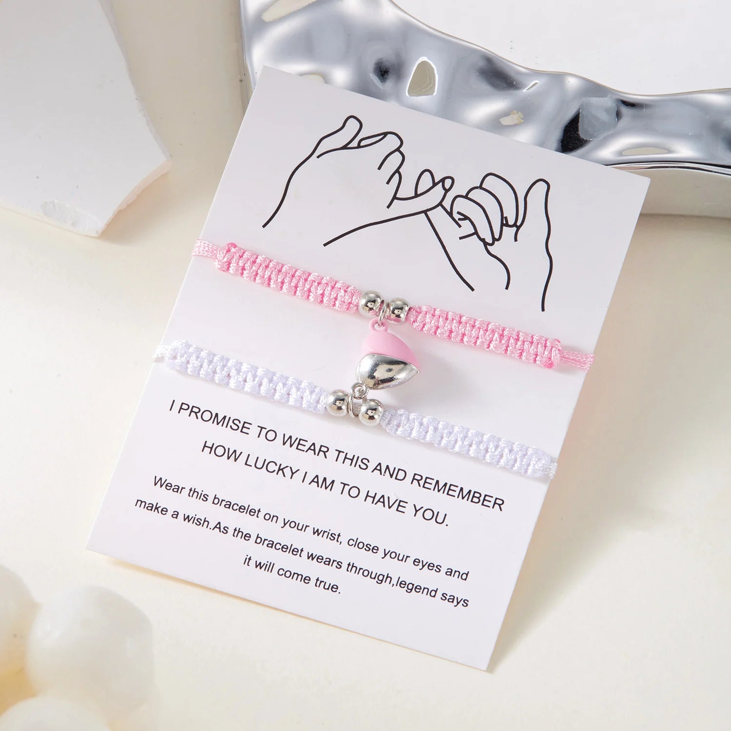 Bracelet with pink and white design on a card with text, on a light background