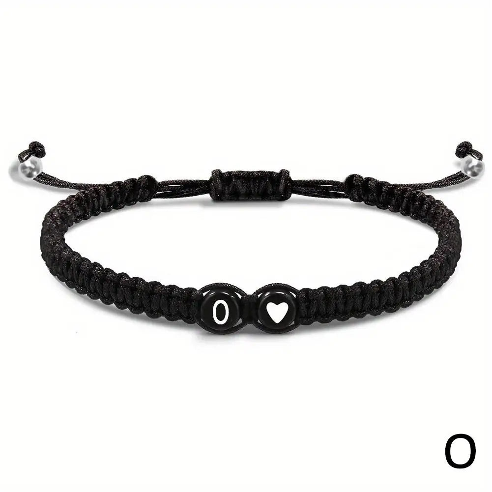 Black braided bracelet with heart and circle charm on a white background