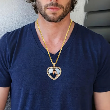 Man wearing a blue shirt with a gold chain necklace featuring a heart-shaped pendant.