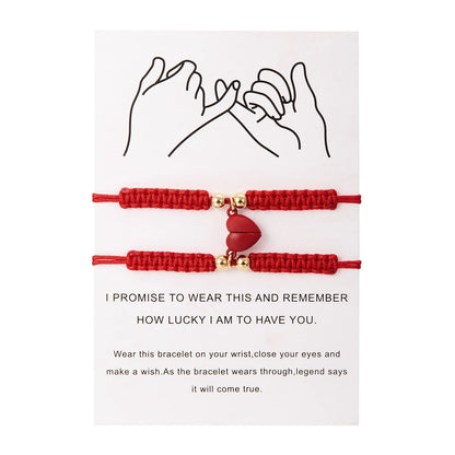 Red bracelet with a heart charm on a white card with text and line drawing of hands.
