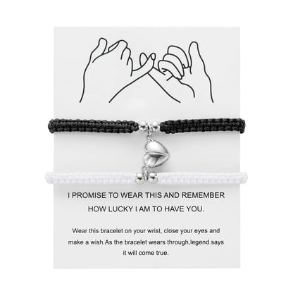 Black braided bracelet with a silver heart charm on a white card with text