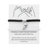Black braided bracelet with a silver heart charm on a white card with text
