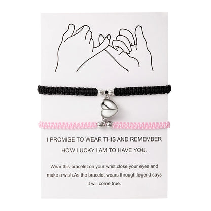 Black and pink bracelet with a heart charm on a white card with text.